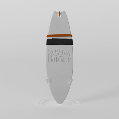 Mini foam surfboard on a clear plastic stand made from recycled materials, branded Aloha Tinyboards™