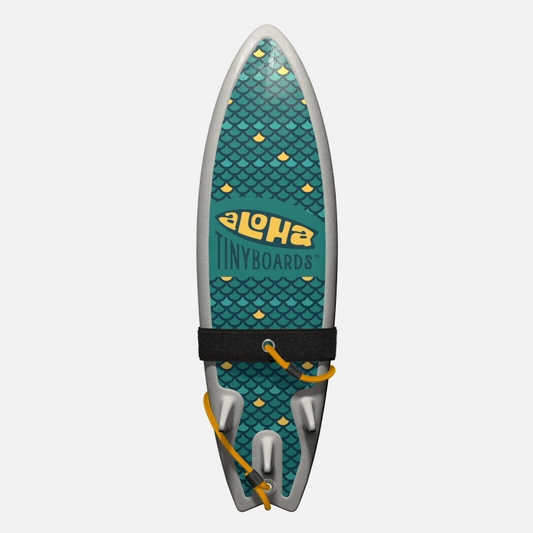 Animated GIF of Aloha Tinyboards foam finger surfboard rotating 360° showing the Fish Scales repeating teal-and-yellow scale motif.